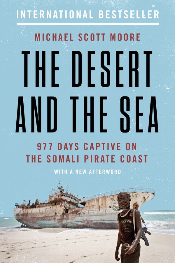 The Desert and the Sea by Michael Scott Moore, a memoir book cover featuring a man and a large, beached boat on a light blue background.
