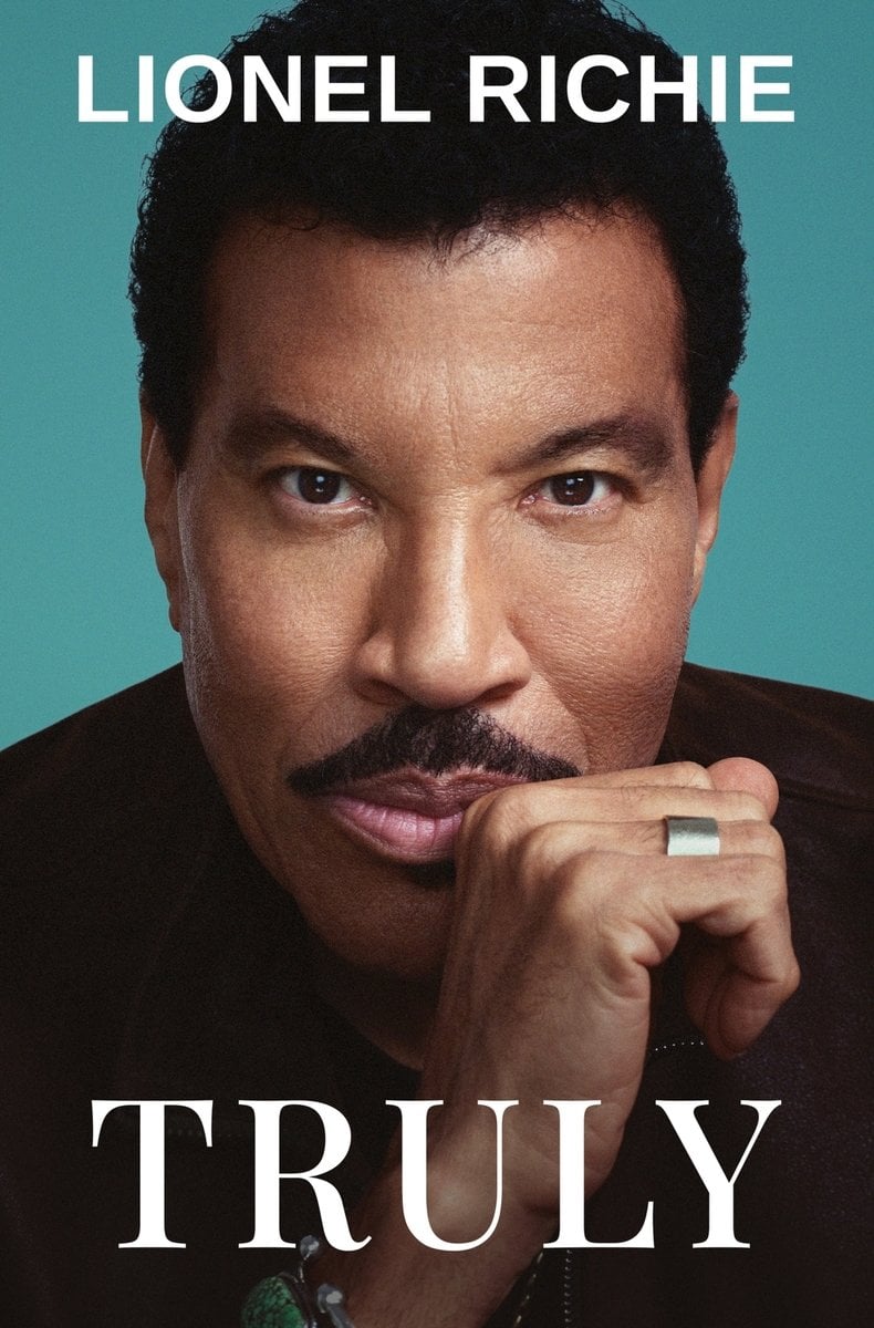 Truly by Lionel Richie, book cover. Portrait of Lionel Richie wearing a black shirt staring straight ahead as he holds an open fist against the side of his mouth.