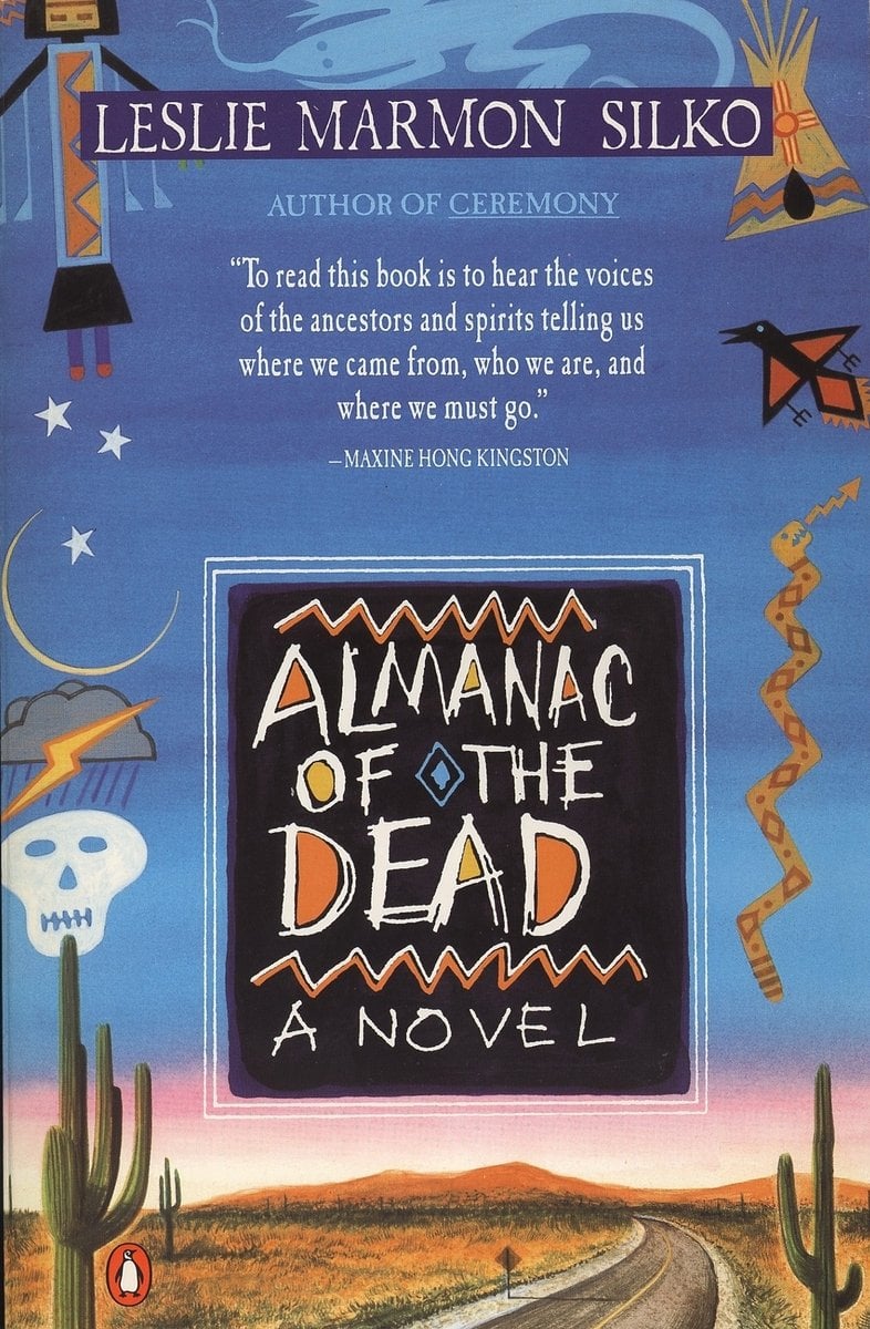 A canyonesque road under a blue sky. There are symbols bordering the background, with the title on a black square towards the bottom. The title is in many different colors, most predominately white. The author's name is white on a line of dark blue at the very top. There is praise is off-white below the author name.