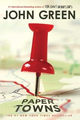 A book cover centering on a large red thumbtack stuck into a close-up of a map, displaying the title of the novel as a place on the map: "Paper Towns". "John Green" is written at the top.