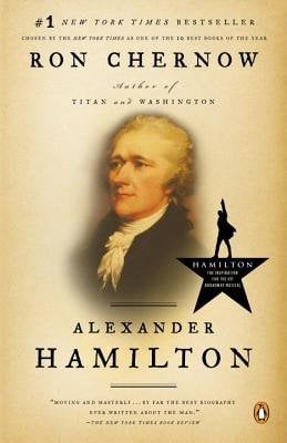 The bust of a man with white hair, wearing a black jacket with a ruffled white shirt underneath. The man is centered on a gold background. To the side is a silhouette of a man raising his arm standing on a portion of a star.