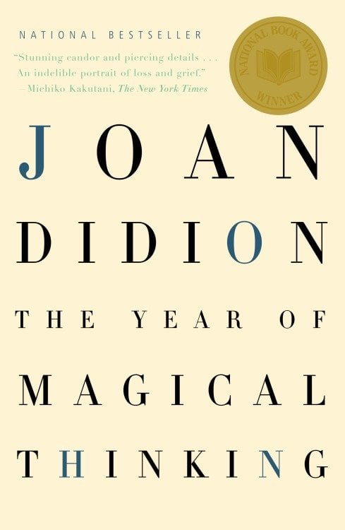 The book cover for The Year of Magical Thinking by Joan Didion. A cream background with the title and the author's name in black and blue text. In the upper right corner is a medal for the National Book Award.