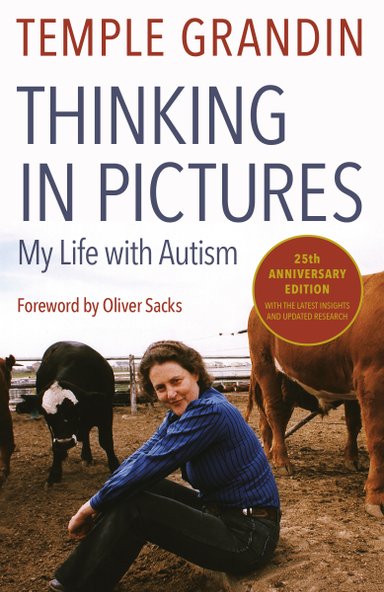 Temple Grandin sitting down beside cows in a fenced in area. She's wearing a striped blue shirt, denim jeans, and a friendly smile.