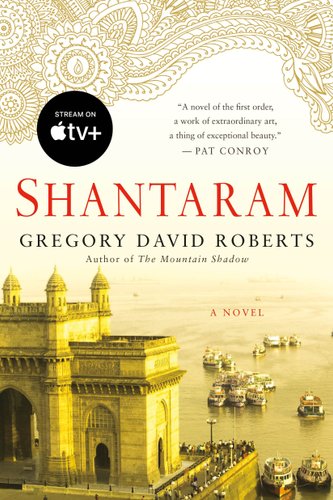 Cover of Shantaram that features a large building in a yellow tint and a waterway with boats behind.