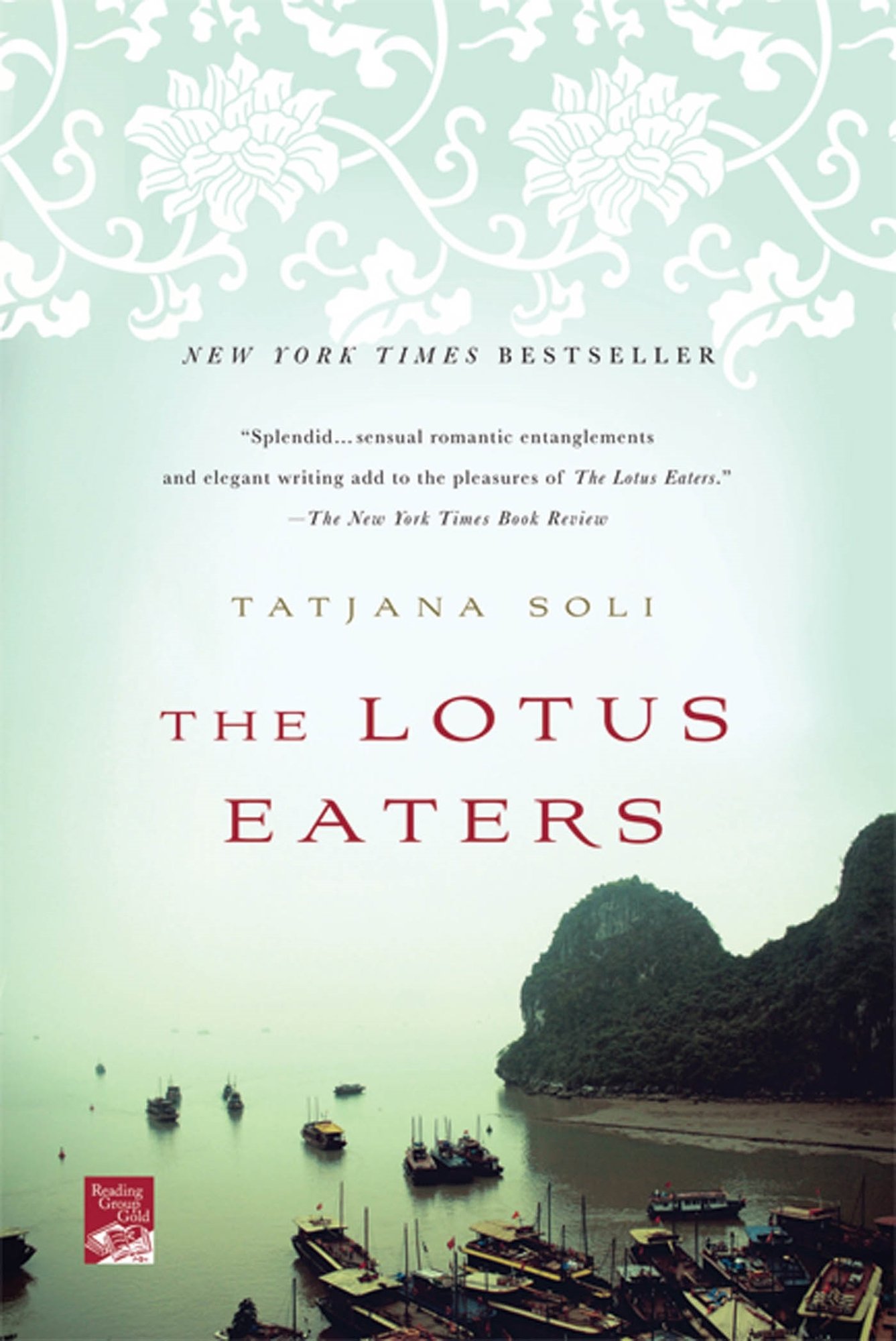 The Lotus Eaters by Tatjana Soli. White floral pattern on a light blue background blends from the top of the cover down into the sky of a shoreline landscape with boats.