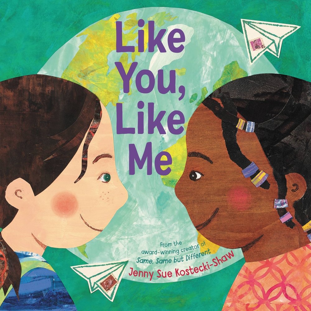 Book cover of "Like You, Like Me" by Jenny Sue Kostecki-Shaw, featuring two children smiling at one another with a globe and paper airplanes with stamps in the background. The child on the left is pale-skinned, brunette with green eyes; the child on the right is brown-skinned, brown-eyed with black hair decorated with colorful beads.