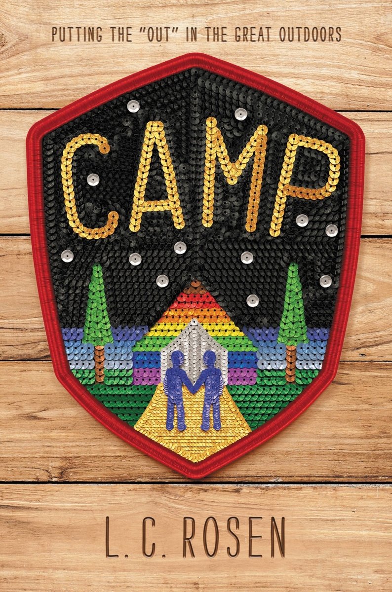 Camp by L.C. Rosen, book cover. A scout patch is on top of a wooden background. The patch contains a night sky with a rainbow house at the end of the pavement as two people hold hands.