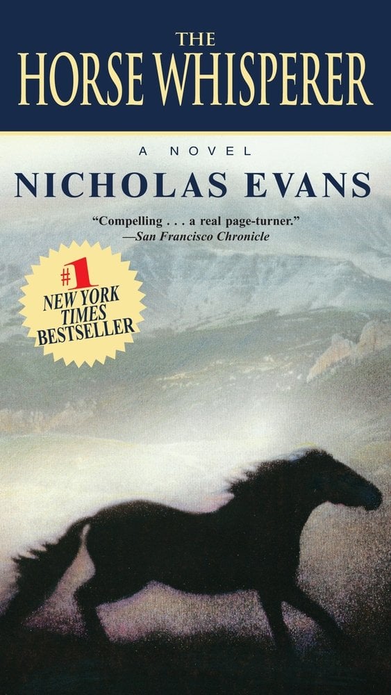The Horse Whisperer by Nicholas Evans book cover depicting a horse running in a field with a mountain scene behind it.