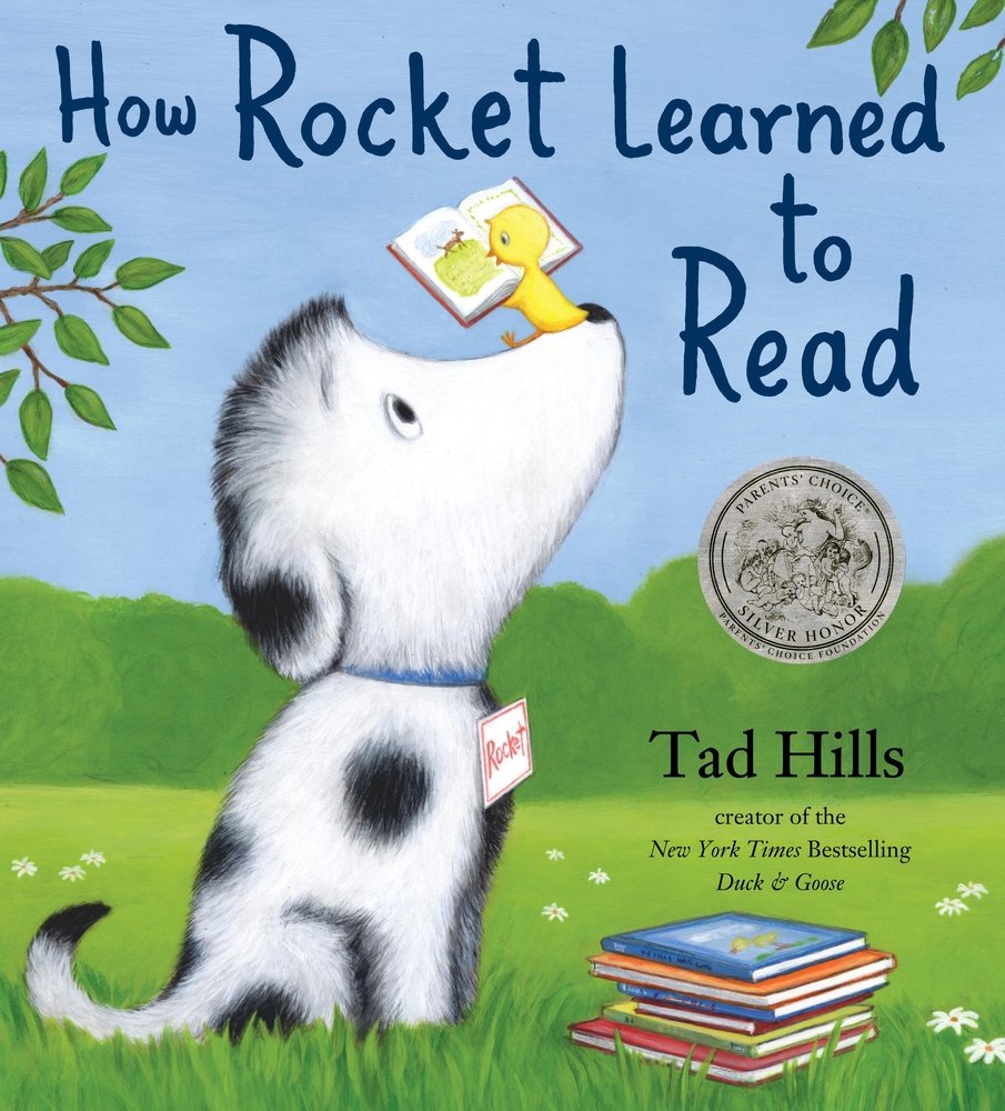 Book cover of "How Rocket Learned to Read" by Tad Hills featuring a white dog with black spots in a seated position with a small yellow bird holding an open book perched on this nose; a small pile of books rests in the grass near them.