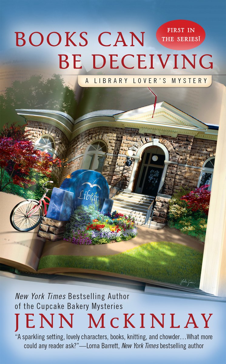 Cover of the cozy mystery book Books Can Be Deceiving by Jenn McKinlay. The background is blue, with a book open on it. There is a realistic image of a brick building in the book, with a bike, and greenery. There is a sign saying that the building is a library.