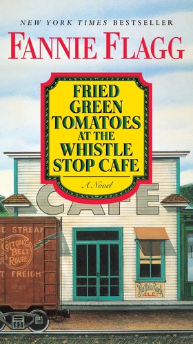 The front of a white building with green trim that is labeled "cafe". A train car is partially seen going in front of it.