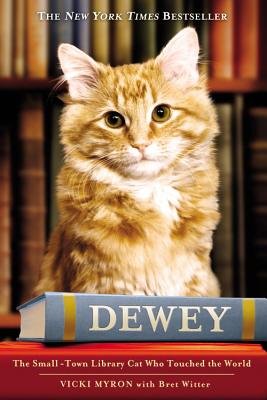 Book cover of Vicki Myron's Dewey: The Small-Town Who Touched the World. The cover depicts Dewey Readmore with two hardcover books in front of him; the book's title is printed across the hardcovers' spines.