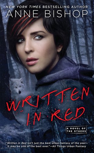 "Written in Red" by Anne Bishop book cover, Meg overlooking her shoulder in the middle of dark woods, behind a tree is a white wolf looking at Meg.