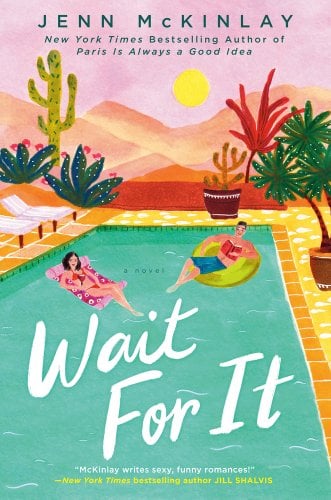 Book jacket for Wait For It by Jenn McKinlay. A man and a woman relax on floats in a pool. Behind the pools is a desert with sandy mountains and several wild and potted varieties of cactus near the pool. The woman is in a pink bathing suit, holding a wine glass on a pink float. The man is reading a red book in blue swim shorts, and is on a green float. White pool chairs line the left of the pool, and potted cacti and trees line the right.