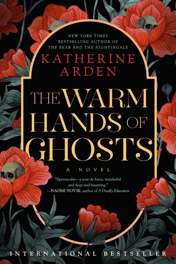 Book cover for The Warm Hands of Ghosts by Katherine Arden depicting a black background with large red flowers scattered around, and skulls peeking from the centers. There is a curved yellow frame around the author name and title.