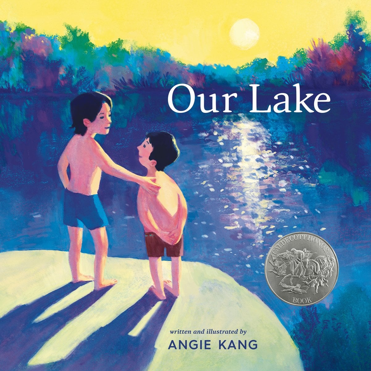 Book cover of Our Lake by Angie Kang, featuring two light-skinned children with short black hair and wearing swimsuits; the older, slightly larger child with their hand on the smaller child's shoulder. They stand on the shore of a blue lake surrounded by foliage.