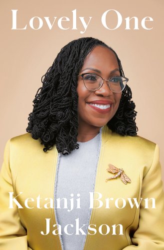 Lovely One by Ketanji Brown Jackson, book cover. The warm, light brown background behind Justice Ketanji Brown Jackson as she looks to her right, smiling and wearing her black-rimmed glasses. She wears a gold suit with a darker gold brooch of a dragonfly.