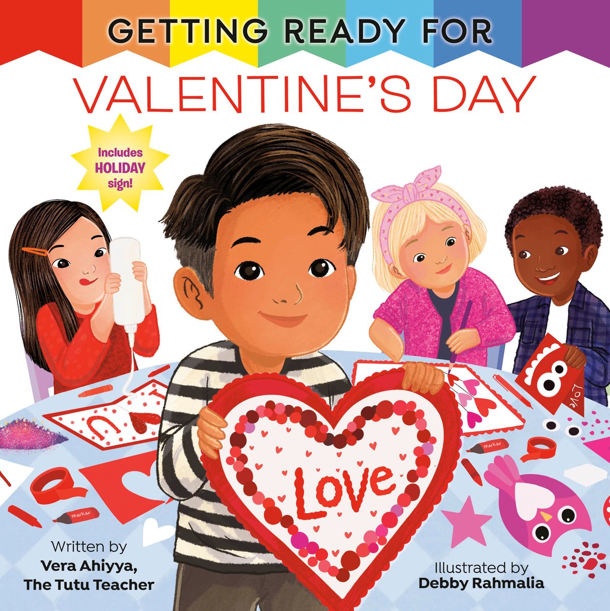 Book cover of Getting Ready for Valentine's Day by Vera Ahiyya, Illustrated by Debby Rahmalia, featuring a brown-skinned child with short dark hair holding up a crafted heart that reads "Love"; behind them are diverse group of children crafting their own Valentine's Day decorations.