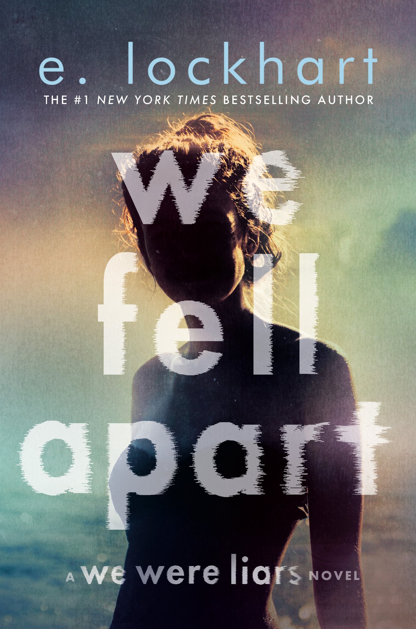 A cover of We Fell Apart by E. Lockhart. There is a blurry girl on the cover standing in front of what looks like an ocean.