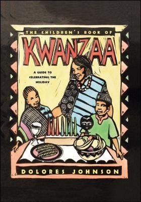 A woman and two children stand around a table with seven candles, a plate of corn and a bowl of fruit. A silver cup and a black African mask sit on the table near the children. They are wearing cultural African clothing and smiling. The title is in large, red lettering above the woman's head. The author's name is in small, yellow lettering at the bottom. A deep black color and pattern make up the background.