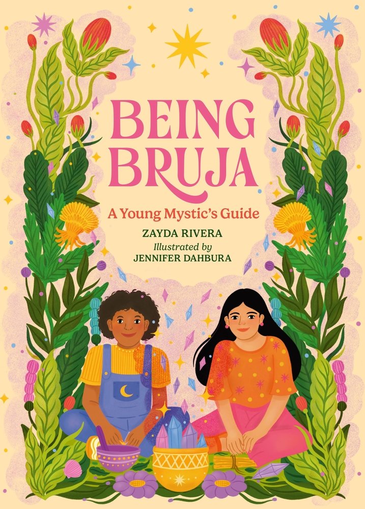 Book cover of Being Bruja: A Young Mystic's Guide by Zayda Rivera, Illustrated by Jennifer Dahbura, featuring a brown-skinned child with short, curly brown hair and a tan-skinned child with long, straight dark hair sitting cross-legged amongst flowers, crystals, and painted pottery.