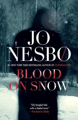"Blood on Snow" by Jo Nesbø book cover of a shadowed man in a wintery, forest landscape. The title of the book is bolded in red, the words "blood" and "on" are red while "snow" still has specks of white.