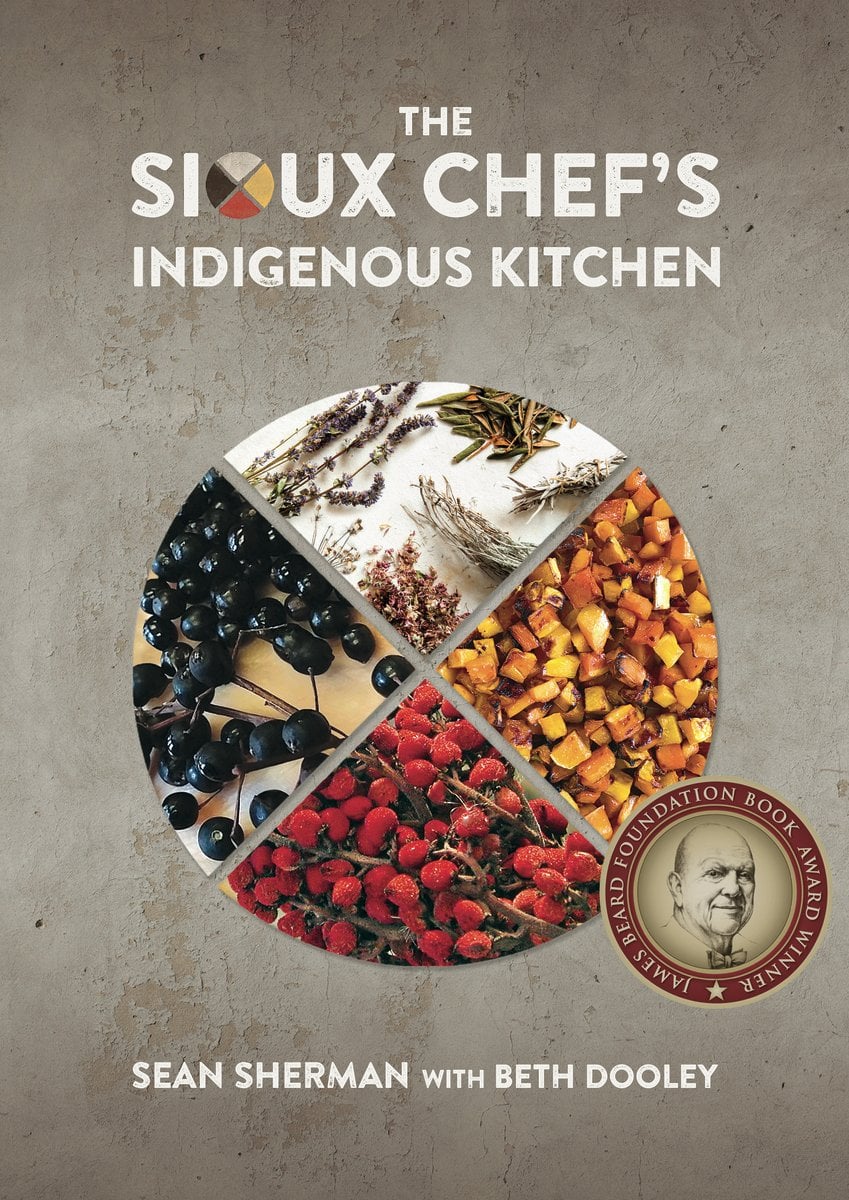 The Sioux Chef's Indigenous Kitchen by Indigenous Chef Sean Sherman book cover of a circle divided into four triangles, like a plate, where each triangle is filled with a picture of ingredients including lavender, herbs, sweet potato, and berries.