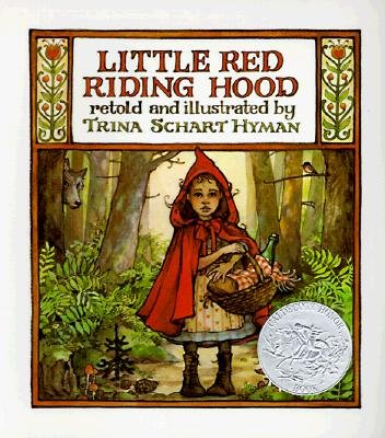 a young girl walks along a dirt path in a forest. She is wearing a dress and a red cloak with a hood. She carries a basket covered with a red cloth. A wolf hides behind a tree watching her. The title sits at the top in red letters. The author's name sits under the title in tan letters.