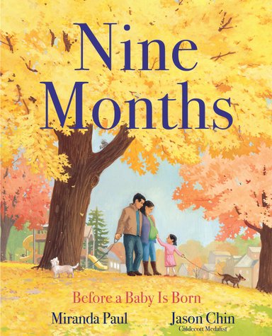 Book cover of Nine Months: Before a Baby is Born by Miranda Paul, Illustrated by Jason Chin, featuring a family of two tan-skinned adults and a tan-skinned child with straight, black hair in a park with towering, autumn-leaved trees; one adult and the child hold the leashes of two small dogs; the child reaches out to touch the other adult's pregnant belly.