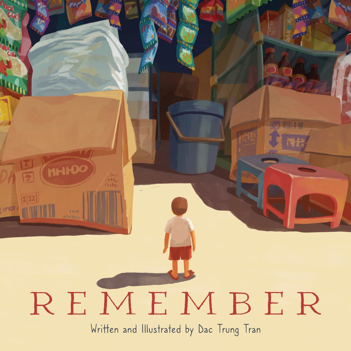 Book cover of Remember by Dac Trung Tran, featuring a tiny light-skinned child staring up at a giant market storefront; large boxes with Vietnamese writing and display cases tower over them.