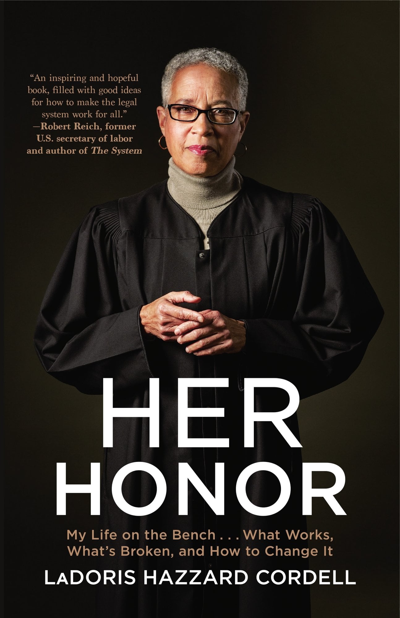 Her Honor by LaDoris Hazzard Cordell nonfiction book cover depicting a Black woman dressed in judge robes and a gray turtleneck with her hands folded slighting at her midsection standing against a dark brown background.