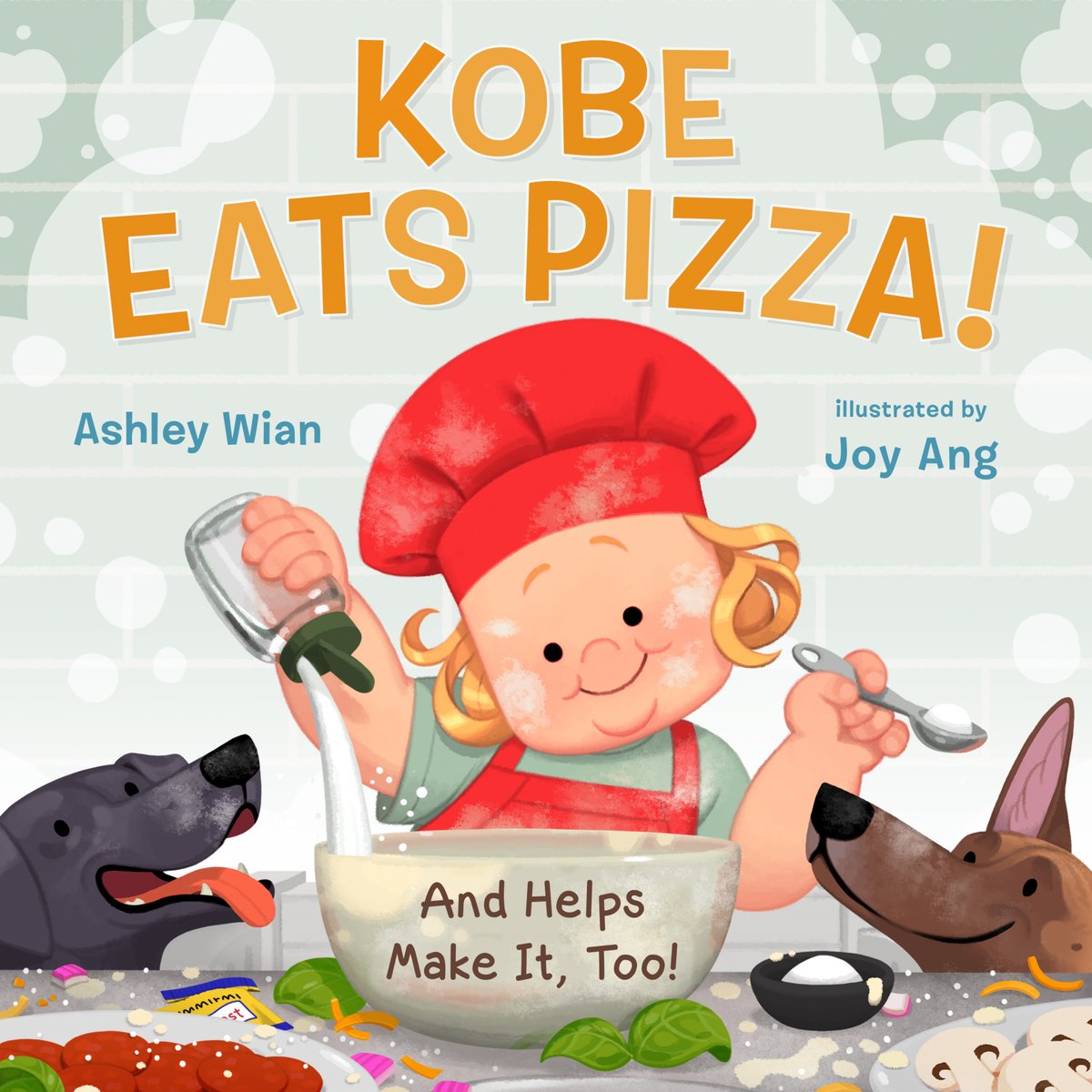 Book cover of Kobe Eats Pizza! by Ashley Wian with Cate Berry, Illustrated by Joy Ang, featuring a light-skinned child with blonde hair wearing a red chef's cap pouring ingredients into a mixing bowl; two dogs watch his actions from either side.