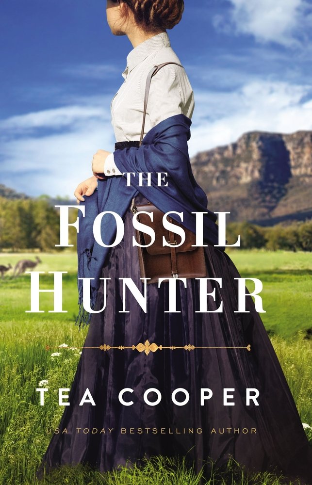 The Fossil Hunter by Tea Cooper. A woman in a skirt, collared shirt, and shawl holds a bag as she stands in a field of grass, looking back at mountains, trees, and kangaroos behind her.