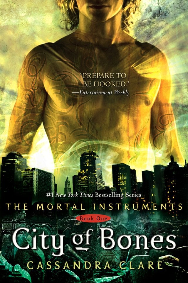 Cover of City of Bones by Cassandra Clare. A shirtless man with medium blonde hair is in the background. In the foreground is a dark city skyline. Light seems to radiate from the man's chest.