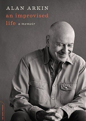 Book cover of "An Improvised Life" with Alan Arkin sitting and smiling in black and white on a gray background.