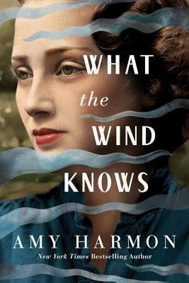 Book cover for What the Wind Knows by Amy Harmon depicting an image of a woman with brown 1920s style hair and light skin wearing a blue top. She is looking off to the side, and there are transparent blue-grey waves scattered around the cover.