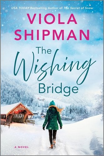 The Wishing Bridge by Viola Shipman, book cover. A woman bundled up in a green coat, yellow scarf, and teal hant walks toward a snow-filled town with a wooden building with lights brimming its roof on the corner.