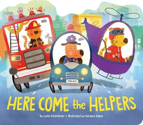 Here Come the Helpers by Leslie Kimmelman, Illustrated by Barbara Bakos, book cover. Three animals are driving three different emergency vehicles. A cat is driving a firetruck in uniform, a dog is driving a police car also in uniform, and a leopard is flying a helicopter. The background is depicted as a city.