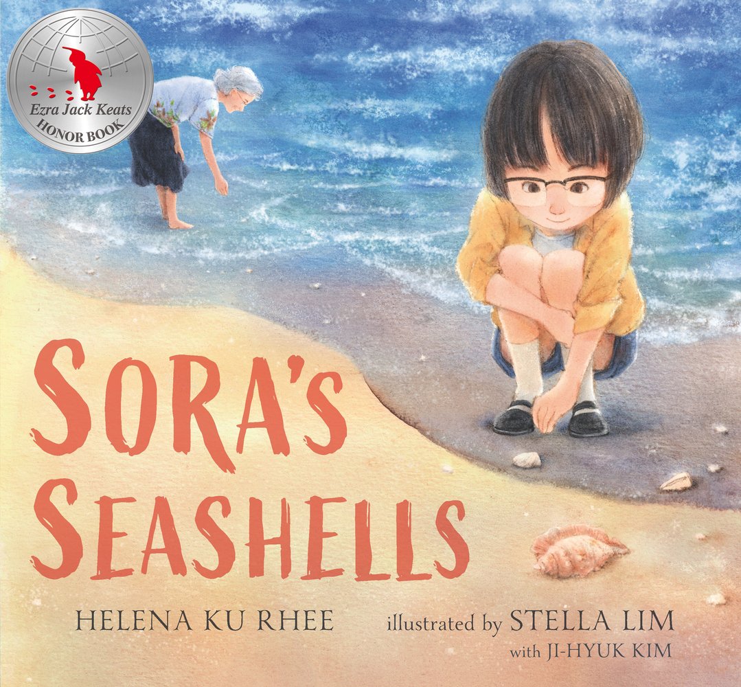 Book cover of Sora's Seashells by Helena Ku Rhee, Illustrated by Stella Lim with Ji-Hyuk Kim, featuring a light-skinned girl with short dark hair crouches on a beach right next to the waves, reaching down for a small white seashell; an elderly woman in the background reaches down from a standing position towards the beach as well.