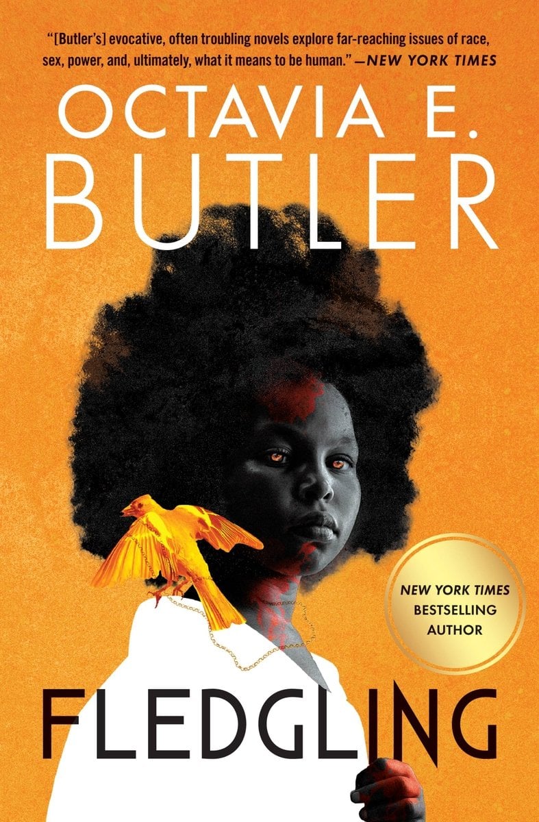 The book cover for Fledgling by Octavia E. Butler. The background is a yellow orange with a Black woman with a large afro in the center. Her skin is gray with red splotches and her eyes are amber. She wears a white shirt and has a golden bird perched on her shoulder.