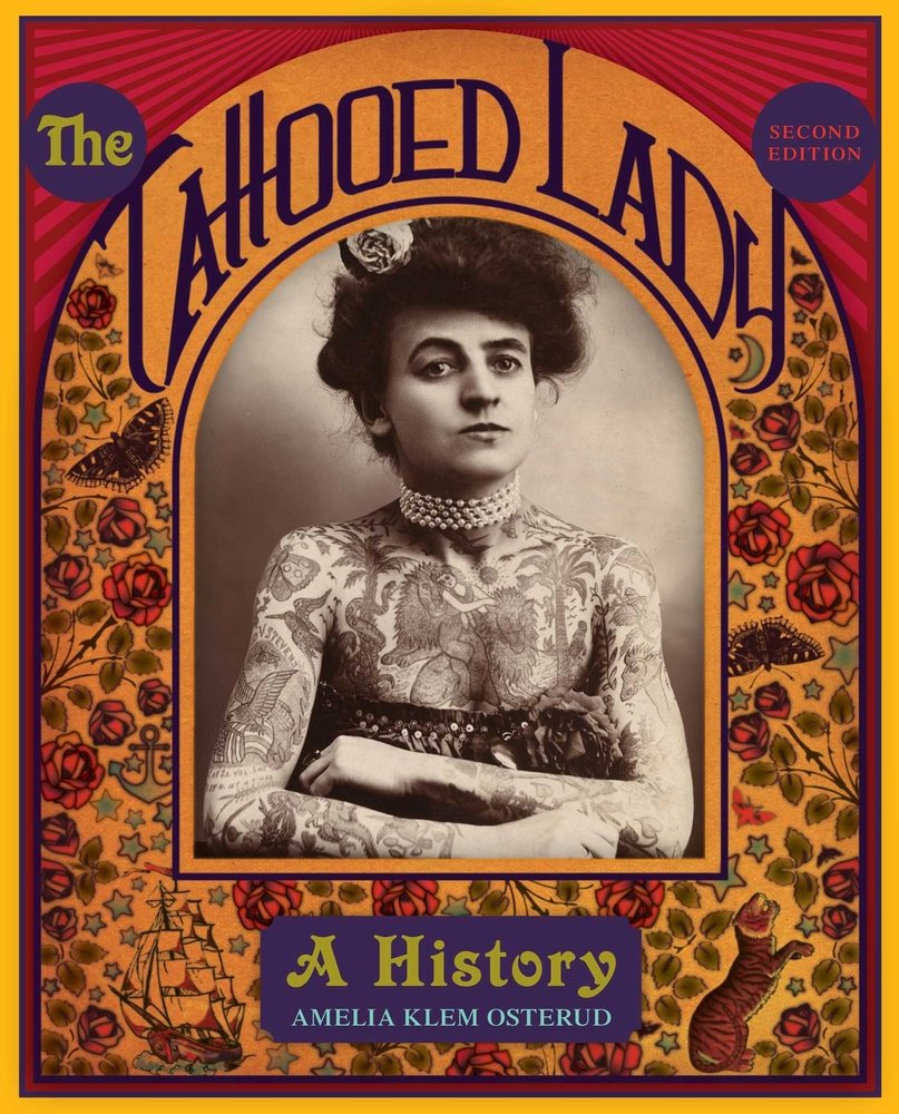 The Tattooed Lady: A History by Amelia Klem Osterud shows a black and white photo of a tattooed lady surrounded by illustrations of flowers, butterflies, and a ship and cat.
