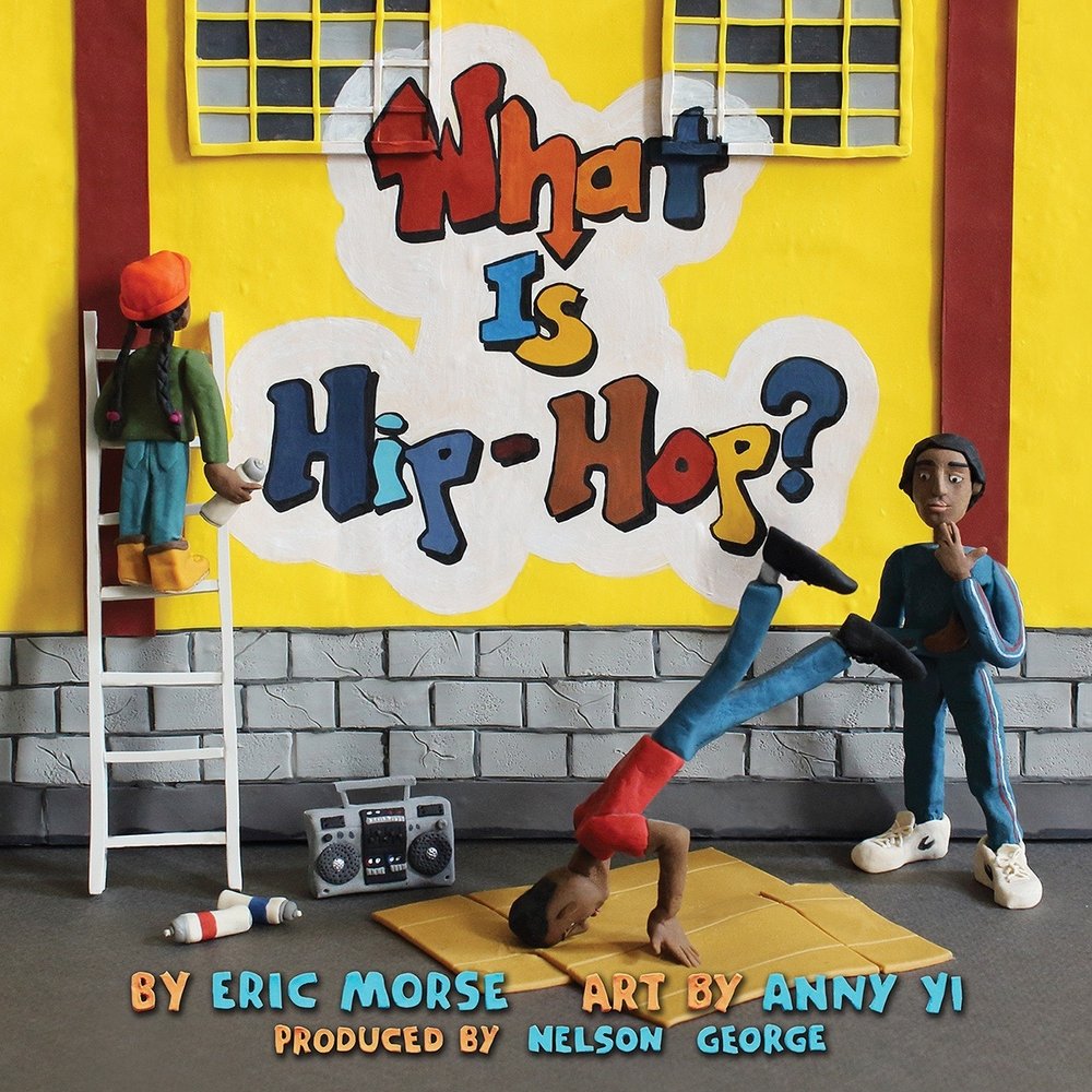 Book cover of What Is Hip-Hop? by Eric Morse, Illustrated by Anny Yi, featuring three brown-skinned human figures; one is b-boy dancing on cardboard to music from a boombox, another watching them, and the third at the top of a ladder having just spray-painted the title on a building wall.