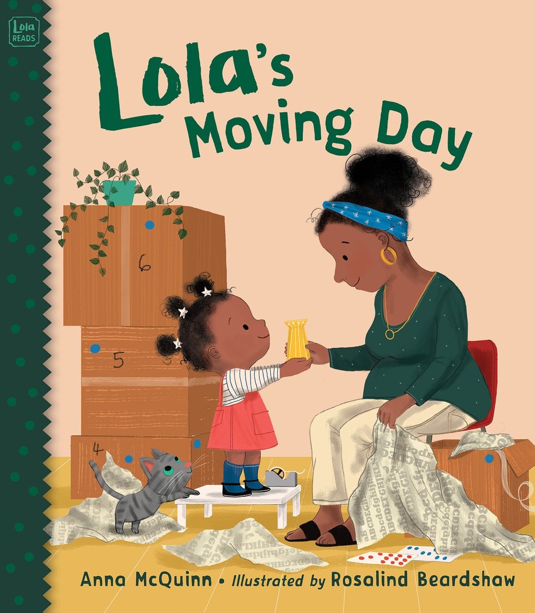 Book cover of Lola's Moving Day by Anna McQuinn, Illustrated by Rosalind Beardshaw, featuring a brown-skinned adult with dark curly hair in a bun taking a small yellow item from a brown-skinned child with dark curly hair in three afro poofs; they are surrounded by moving boxes.