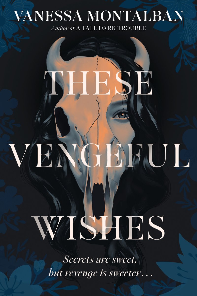 The book cover for These Vengeful Wishes by Vanessa Montalban. A black background framed by dark blue flowers. In the center, a woman's head with black hair and pale skin peers out from behind a horned animal skull.