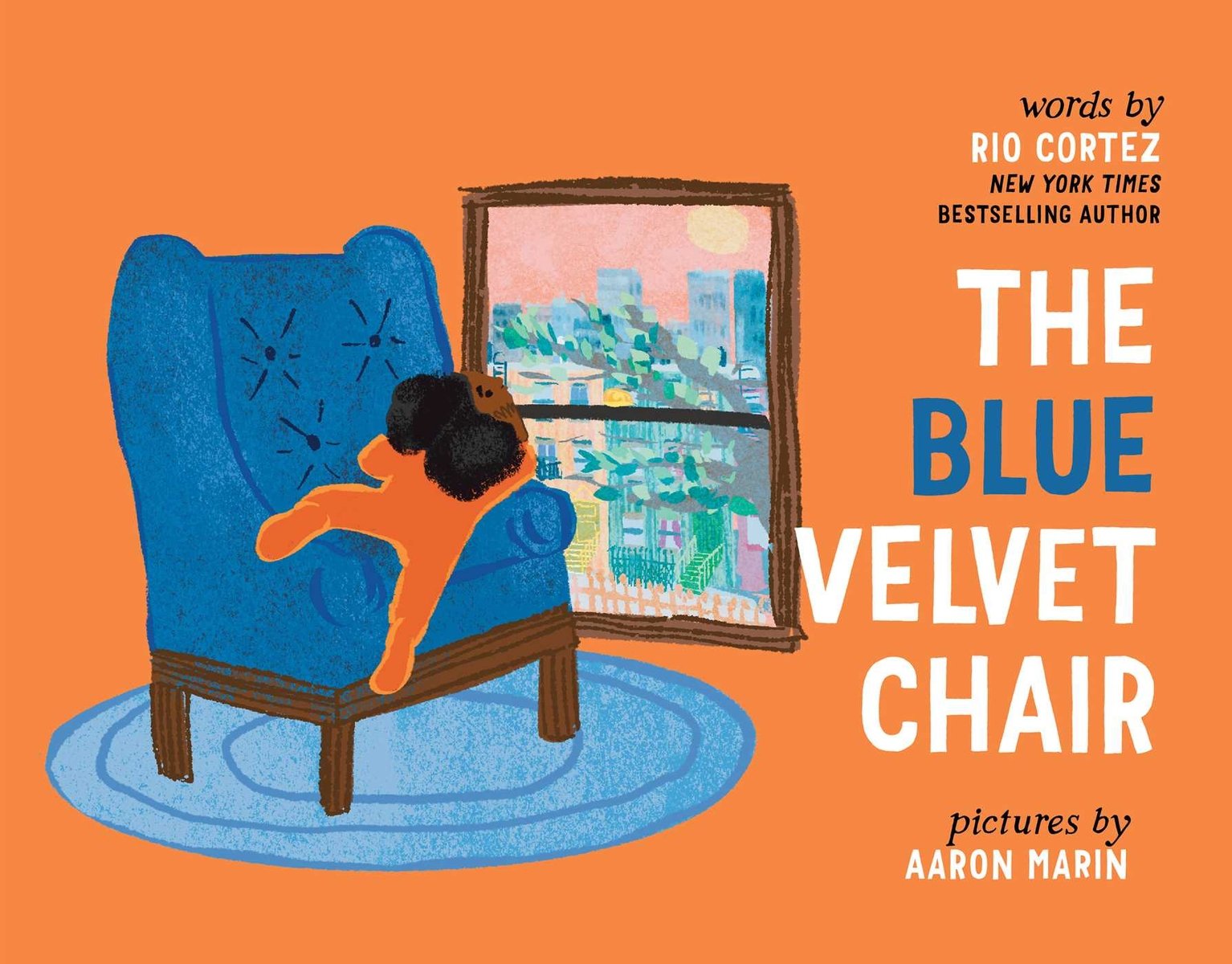 Book cover of The Blue Velvet Chair by Rio Cortez, Illustrated by Aaron Marin, featuring a brown-skinned child with curly black hair lounging in a blue armchair while staring out a window at a cityscape.