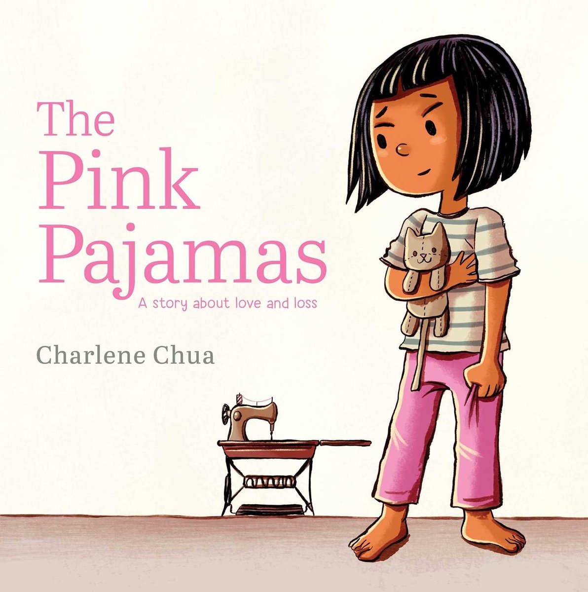 Book cover of The Pink Pajamas: A Story About Love and Loss by Charlene Chua, featuring a tan-skinned child with chin-length, straight black hair holding a cat plushie and looking back at a pedal sewing machine in the distance.
