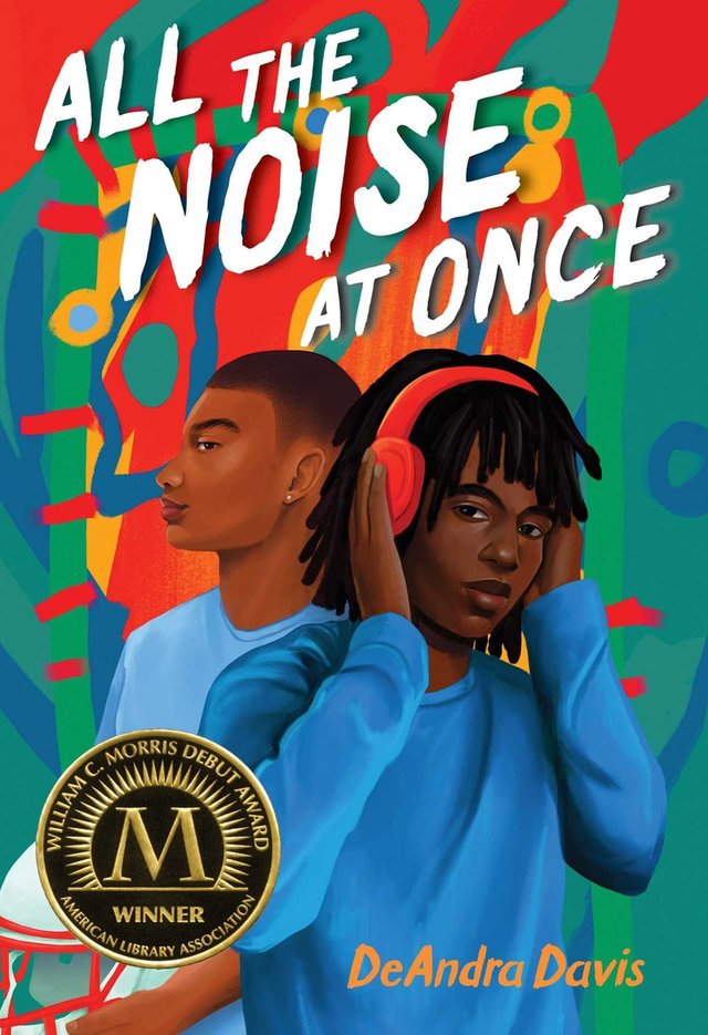 All the Noise at Once by DeAndra Davis, book cover. Two boys in blue clothing are in the center, the background is an abstract design of green, red, and orange coloring. One boy is holding a football helmet with a buzz cut; the other has his hands on the red headphones on his head with locs.