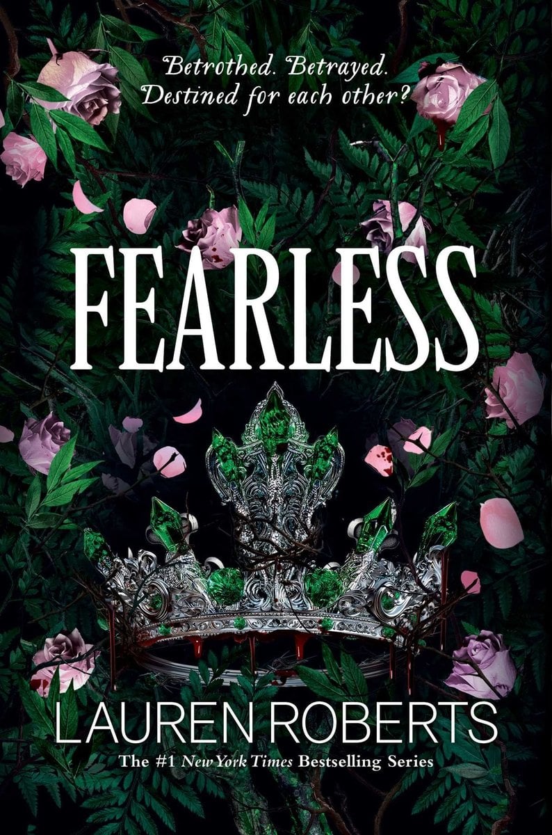 Fearless by Lauren Roberts cover displays a shadowy wall of green ferns and thorny vines, a detailed silver crown studded with bright emerald-green stones sits ensnared in dark branches, with pink rose blooms and scattered petals around it. The white title spans the upper half. A tagline reads, ‘Betrothed. Betrayed. Destined for each other?’ At the bottom, Lauren Roberts name is in all caps and white.