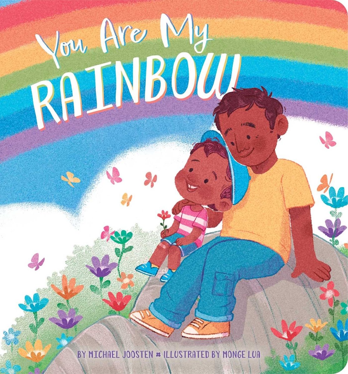 Book cover of You Are My Rainbow by Michael Joosten, Illustrated by Monge Lua, featuring a brown-skinned adult with short brown hair sitting on a rock with a brown-skinned child with short, curly brown hair as both look up at a rainbow.