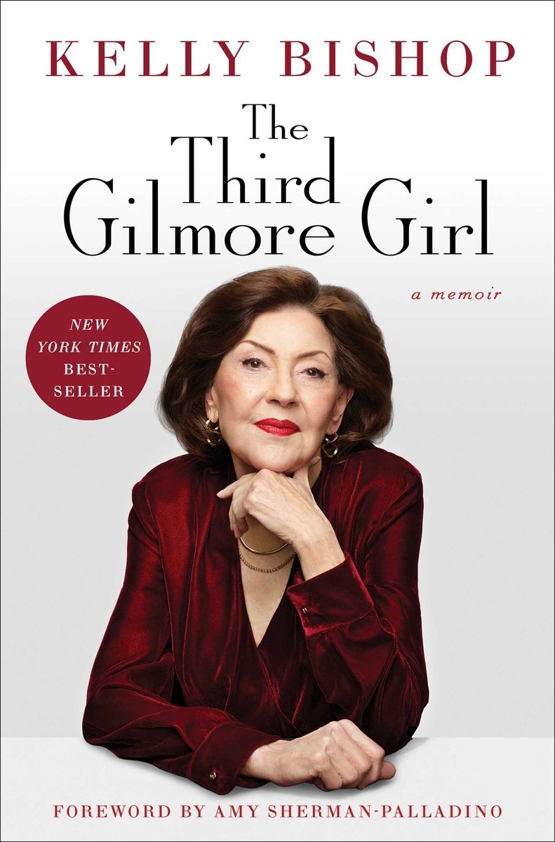 The book cover for The Third Gilmore Girl by Kelly Bishop. A white background. In the center, a photo of Kelly Bishop in a red blouse leaning with her chin on her hand.